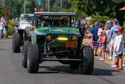Custom off-road vehicles drive past spectators during the Fourth of July parade in Home, Washington.